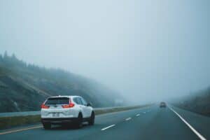 A Car driving cautiously on a foggy road